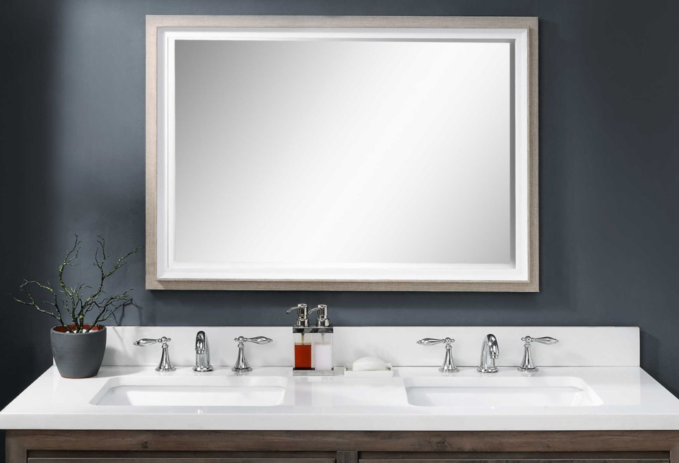 A bathroom vanity is shown with a rectangle mirror and dark blue walls.